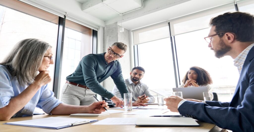 Finance team of 5 men and women around a conference table discussing ERP migration