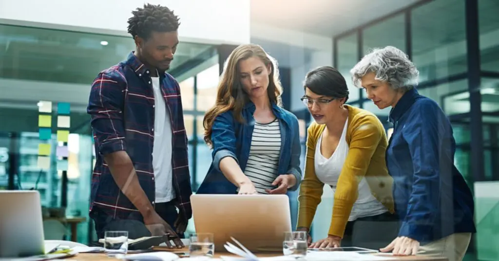 Diverse group of business people gathered around laptop computer in office to plan Dynamics 365 Business Central Integration